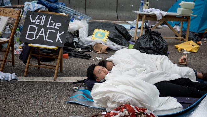 Pro-democracy protesters sleep next to a sign that reads "We'll be back" on a blocked road in the Admiralty district of Hong Kong on Dec. 11, 2014.