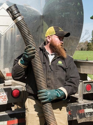 South African immigrant Malcolm Fourie holds a hose after pumping fertilizer into a sprayer in Iredell County, N.C.