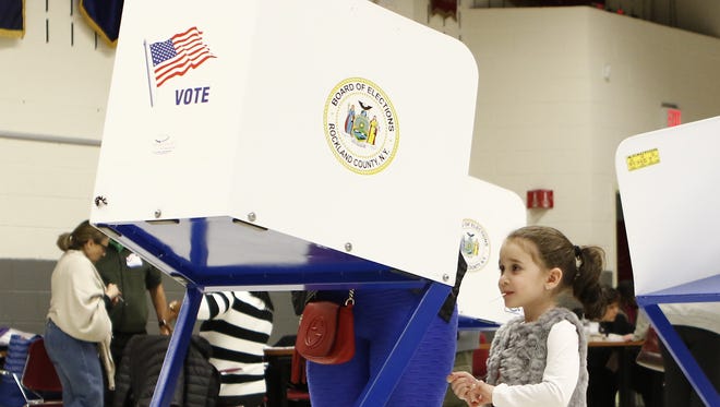 A young girl watches her mother cast her ballot at the Rockland County Fire Training Center in Pomona on Nov. 8, 2016.