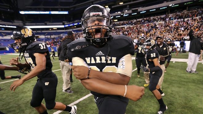 Warren Central player Davonte Guthrie and his teammates rush the field in celebration after beating Carmel in the IHSAA Class 6A State Football Finals held at Lucas Oil Stadium on Nov. 30, 2013.