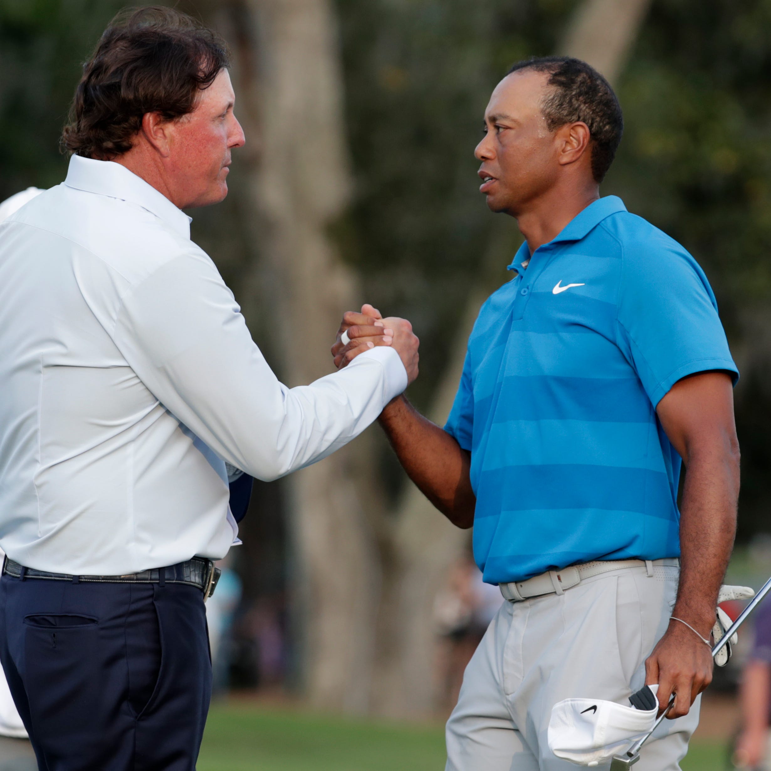 FILE - In this May 10, 2018, file photo, Phil Mickelson, left, and Tiger Woods shake hands after the first round of the Players Championship golf tournament, in Ponte Vedra Beach, Fla.  The winner-take-all match between Tiger Woods and Phil Mickelson