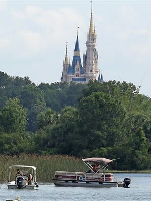 In the shadow of the Magic Kingdom Florida Fish and Wildlife Conservation Officers search for the body of a young boy Wednesday, June 15, 2016 after the boy was snatched off the shore and dragged underwater by an alligator Tuesday night at Grand Floridian Resort at Disney World in Lake Buena Vista, Fla. (Red Huber/Orlando Sentinel via AP)    