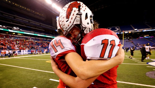 New Palestine’s Zach Neligh (14) comforts quarterback Alex Neligh (11) after a tough loss in the Class 5A IHSAA Football State Tournament finals against  Fort Wayne Snider at Lucas Oil Stadium on Nov. 27, 2015.