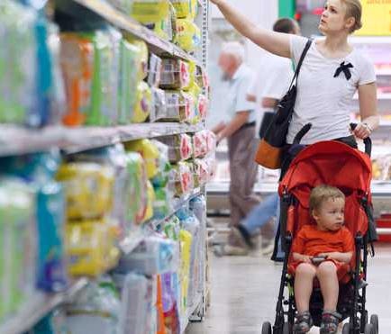 A woman shopping for diapers in the aisle of a store