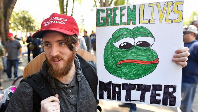Andrew Knight holds a sign of Pepe the frog, a conservative icon, during a rally in Berkeley, California on April 27, 2017.