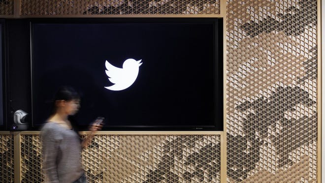 A Twitter icon on a dark wall with a person walking past it