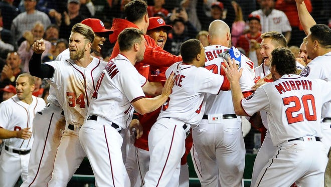 Washington Nationals right fielder Bryce Harper (34) reacts towards home plate umpire Brian Knight (not pictured) as first baseman Clint Robinson (25) is greeted by teammates after hitting walk off homer against the Detroit Tigers.