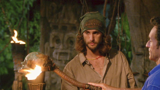 Host Jeff Probst (right) snuffs Alec Christy's Tiki torch after the Tribal Council voted Christy off the reality TV show "Survivor."