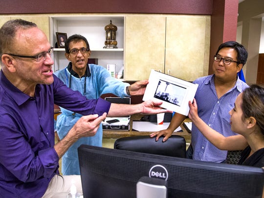Brighter Way Institute Executive Director Kris Volcheck ,left, shows a photo of the original CASS Dental Clinic, which started with two dental chairs in a repurposed trailer, to staff dentist Abbas Fazel, second from left, and dentists Dr. Daniel Nam and Dr. Ashley Cheng at the Brighter Way Dental Center in Phoenix, Friday, July 22, 2016.