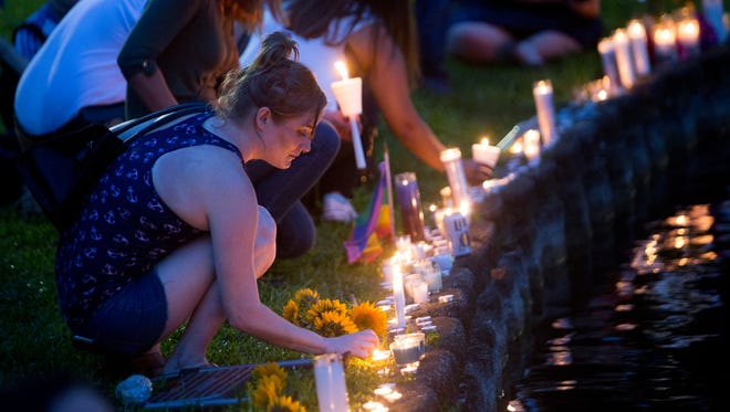 A woman places a candle Sunday at Lake Eola in Orlando during a vigil for those killed and injured in a mass shooting at the Pulse night club.