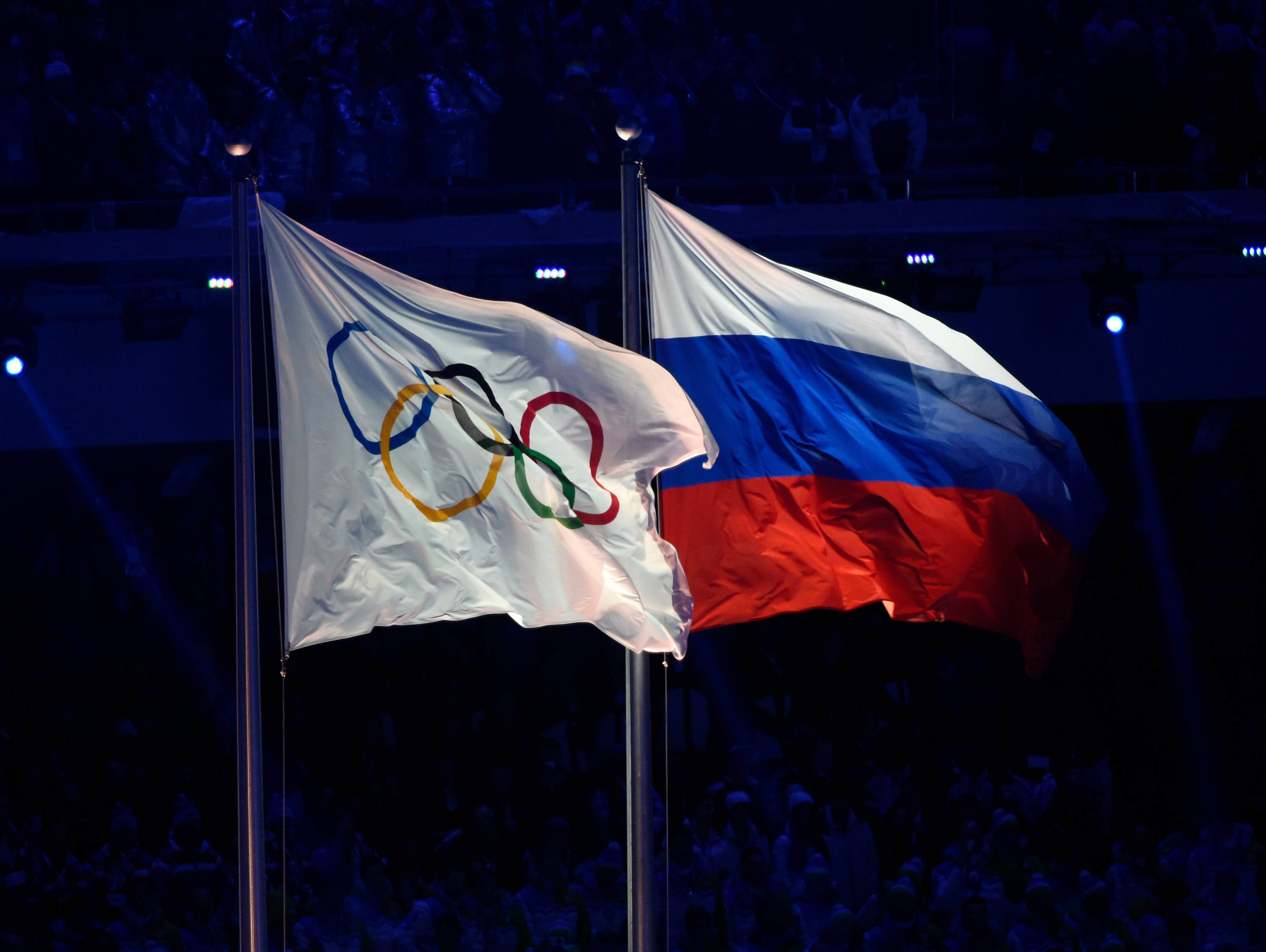 The Olympic flag (left) flies next to the Russian  flag during the opening ceremony for the Sochi 2014 Olympic Winter Games.