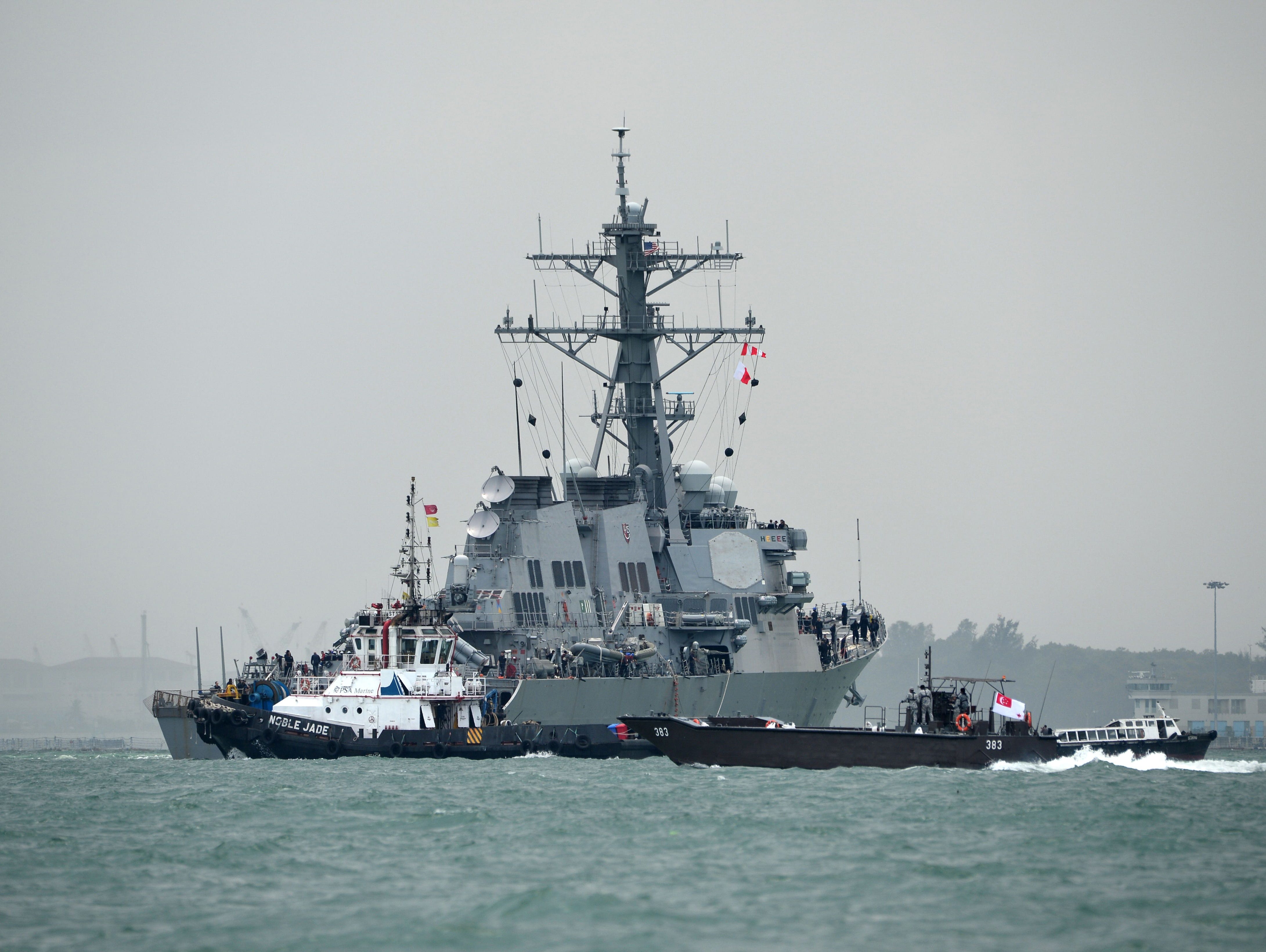 The guided-missile destroyer USS John S. McCain is guided by a tugboat after a collision with an oil tanker, outside Changi naval base in Singapore on Aug. 21, 2017.