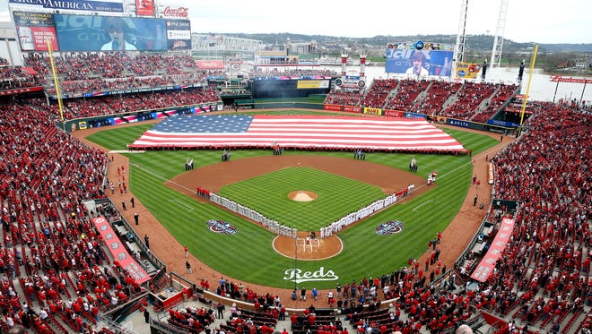 The National Anthem is sung as the American Flag is draped on the field during the Cincinnati Reds Opening Day pregame ceremony at Great American Ball Park Monday April 3, 2017.