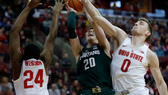 Michigan State guard Matt McQuaid, center, goes up to shoot between Ohio State forward Andre Wesson, left, and center Micah Potter during the first half on Sunday, Jan. 7, 2018, in Columbus, Ohio.