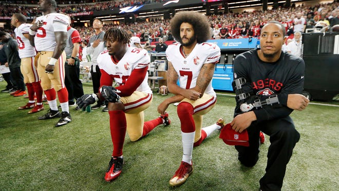 In this Dec. 18, 2016, file photo, San Francisco 49ers quarterback Colin Kaepernick (7) and outside linebacker Eli Harold (58) kneel during the playing of the national anthem before an NFL football game against the Atlanta Falcons in Atlanta. The blackballed quarterback was honored as Week 1 Community MVP by the players' union for his latest $100,000 donation and a back-to-school giveaway in New York City.