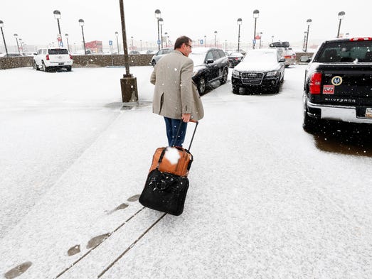 A traveler makes his way to a vehicle as snow covers