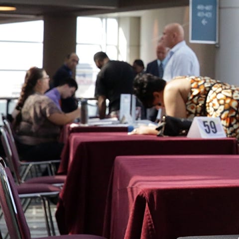 Job seekers fill out applications at a job fair.
