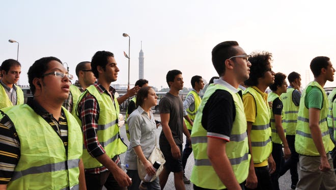 A group clad in bright green vests walks through central Cairo at sunset Monday during the Muslim holiday Eid al-Fitr as part of the  Harassing the Harasser campaign July 28.