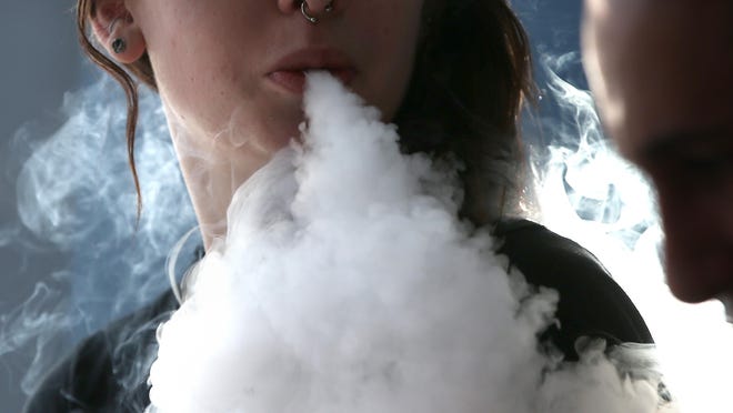 A woman smoking tobacco blows a large cloud of smoke.