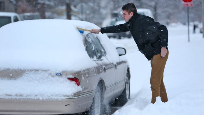 Butler student Kirby Lawson reaches to start cleaning off his car, on Hampton Dr., after an overnight snowfall, Tuesday, January 6, 2015. He is originally from Chicago and had recently spent two hours defrosting his car because his doors were frozen shut. "So here in Indianapolis, I'd take the snow over the cold any day," he said.