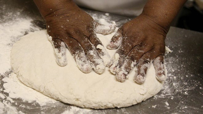 With a well flowered surface Peggy Brown, owner of Peggy's Home Cooking on Cleveland, spreads her biscuit dough out with her hands before cutting them out with a glass.