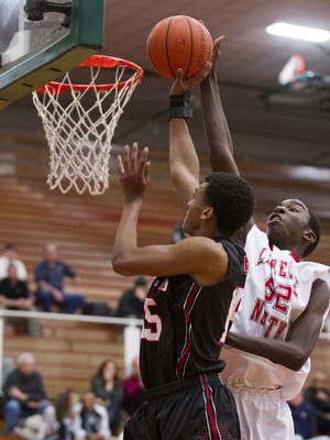 North Central High School sophomore T.J. Walton (25) is fouled by Lawrence North High School sophomore Ra Kpedi (52) as he tries to put up a shot during the first half of action. Lawrence North High School hosted North Central High School in a first-round game of the 2015 Marion County Boys Basketball Tournament, Tuesday, Jan. 13, 2015.