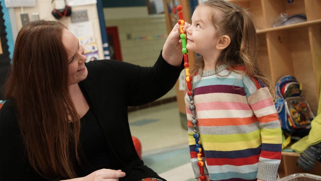 Special education teacher Ashley Bryson checks to see if the building links that 4-year-old Savannah Messick, a preschooler at the Leach School, put together are taller than her.