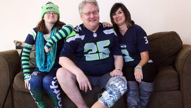 Daniel Nelson, center, shows his personalized prosthetic leg made with with a Seattle Seahawk shirt with wife, Robbin Nelson, right, and daughter Nacole Nelson in their Northeast El Paso home. Nelson was recently fitted with the prosthetic after losing his left leg to vasculitis. It goes without saying. They are Seahawk fans.
