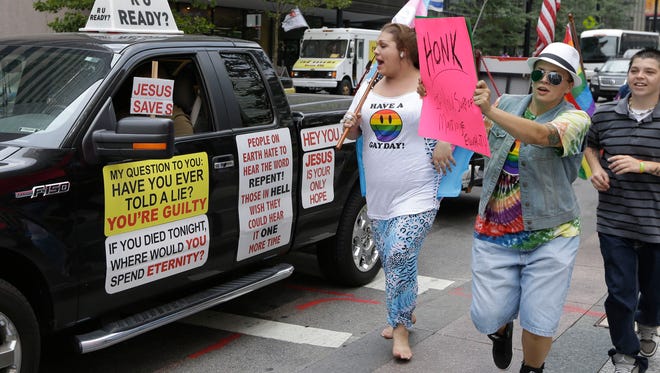 This Wednesday, Aug. 6, 2014, file photo shows gay marriage supporters following an opponent of gay marriage driving his truck around Fountain Square where several hundred gay marriage supporters held a rally in Cincinnati.