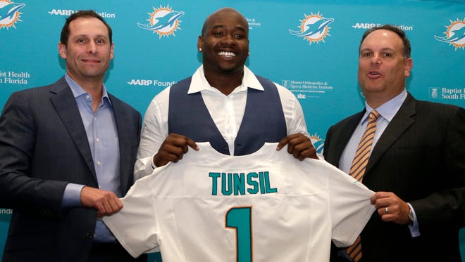 Former Ole Miss offensive lineman and top Miami Dolphins draft pick Laremy Tunsil, center, holds up his jersey as he stand with with head coach Adam Gase, left, and Mike Tannenbaum, executive vice president of football operations, right, following a news conference, Friday, April 29, 2016 in Davie, Fla.