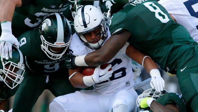 Penn State's Saquon Barkley, center, is tackled by Michigan State's Lawrence Thomas (8), Riley Bullough (30), Montae Nicholson (9) and Darien Harris, bottom right, during the first quarter on Saturday.
