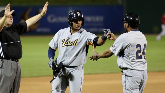 Isaias Tejeda fist bumps with his third-base coach during a Revolution road game. Tejeda is batting nearly .350 this season with an on-base percentage over .400.