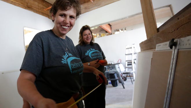 Volunteers Julie Worzella, left, measures a dry-wall while Sherry Kujawa looks on Saturday at Destiny Point house, a women's shelter in the town of Blenker.