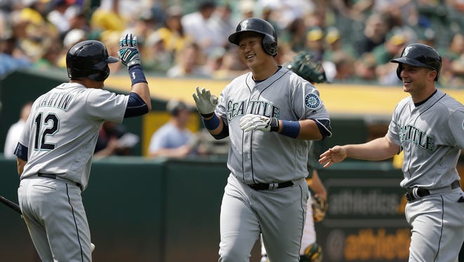 Seattle Mariners' Dae-Ho Lee, center, is congratulated by Leonys Martin (12) and Kyle Seager, right, after hitting a two run home run off Oakland Athletics' John Axford in the seventh inning of a baseball game Wednesday, May 4, 2016, in Oakland, Calif. (AP Photo/Ben Margot)