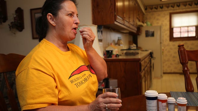 Terri McCulloch seen here at her home taking a multitude of prescription drugs that have helped save her life.