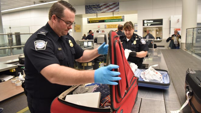 Agriculture customs officers last name Kane, front, and last name Hucko, background, search passengers bag for contraband food items at Newark Airport, on Wednesday, November 9.