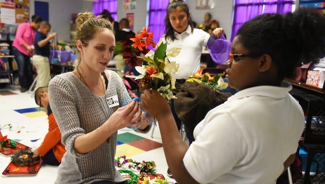 Ellen Keever helps fourth-grade student Ashanti Walker, 9, at Earl Travillion Attendance Center decorate christmas wreaths and bouquets. She also works with the smART Space program and volunteers as she loves to interact with children.