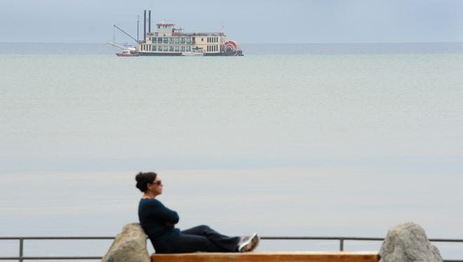 With the stranded Tahoe Queen in the distance, a woman relaxes on Regan Beach Tuesday morning. The tourist stern-wheeler became stranded Monday afternoon, with nearly 300 passengers and 14 crew members safely evacuated.