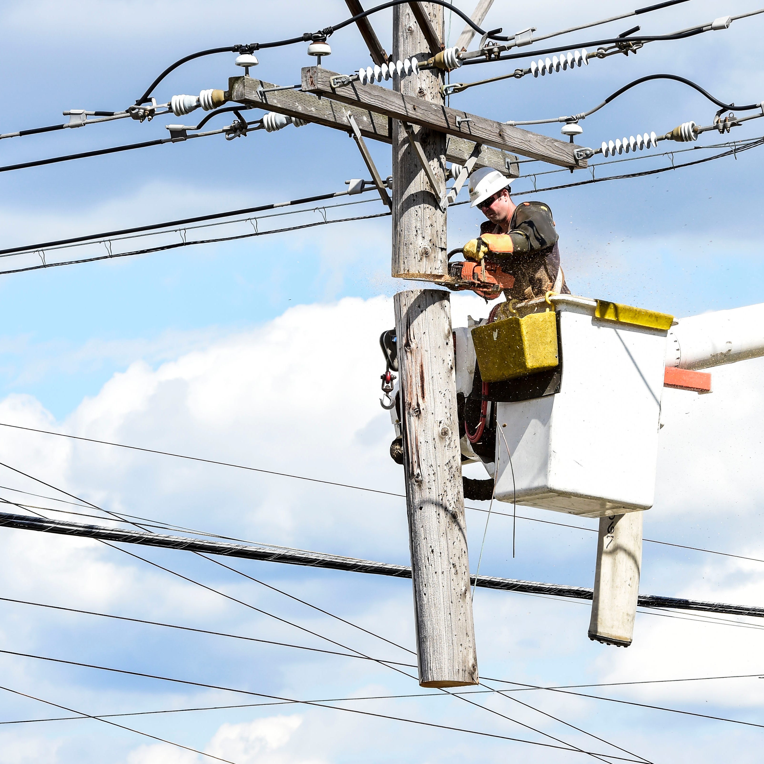 Crews from NYSEG cut a part of the utility pole to remove some of the extra weight off the wires.