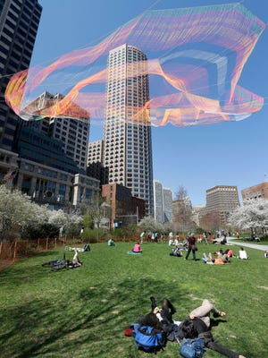 Lushik Wahba, bottom center, and Nare Filiposyan, bottom right, both of Bennington, Vt., look toward a colorful 600-foot sculpture suspended between high-rise buildings above the Rose Kennedy Greenway, Sunday, May 3, 2015, in Boston. The sculpture, that is to remain in place through October 2015, is made from over 100 miles of twine and utilizes over half a million knots. (AP Photo/Steven Senne)