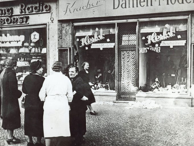 A group of people standing outside a Jewish-owned shop