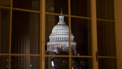 The U.S. Capitol is framed amid reflections from inside the Cannon House Office Building.