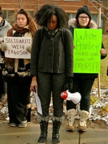 Mariah Urueta, left, Portia Brown, center, and Hannah Mollett, right, have a moment of silence to honor Michael Brown at the campus of Central Michigan University on Tuesday, Nov. 25, 2014.