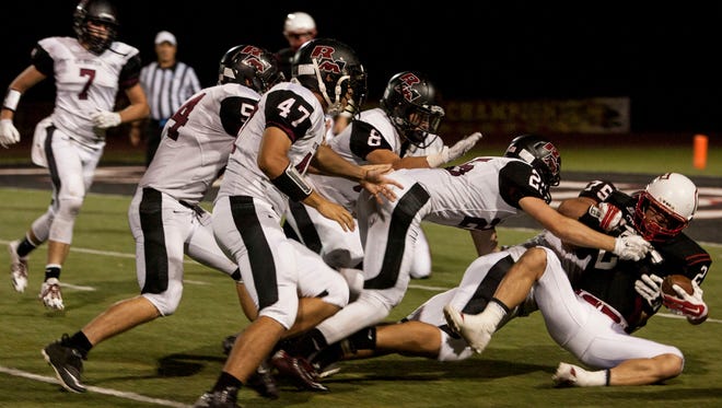 A group of Red Mountain defenders take down Chaparral running back Gabe Lutz (right) during the first quarter on Sept. 26, 2014.