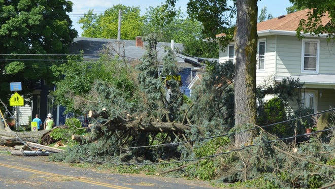 Downed trees and power lines lie among debris following a storm in Columbus July 13. A temporary aid station has been set up at Columbus Middle School. Local fire officials advised against traveling in the city until downed power lines could be cleared. The storms also brought torrential rain to the area, flooding farms and residential yards.