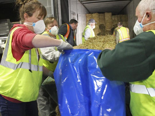 Sarah Koonce, left, of Anchorage, Alaska, and Greg Czarnecki, of Wasilla, Alaska, are among volunteers stuffing bales of hay inside plastic bags in Anchorage on Thursday. About 1,500 bales will be flown to checkpoints along the route of the Iditarod Trail Sled Dog Race, which begins March 7, and put down on the snow and ice so the canine participants have a warm place to sleep.