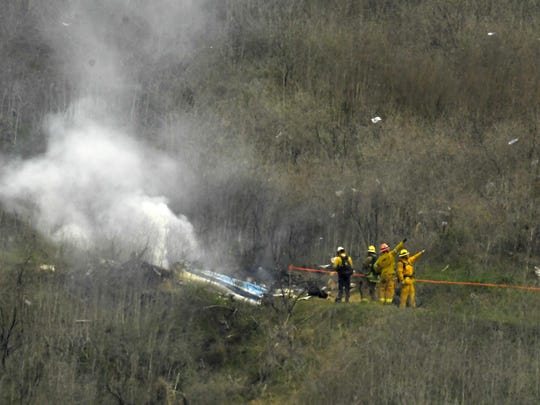 In this Jan. 26, 2020 photo, firefighters work the scene of a helicopter crash where former NBA basketball star Kobe Bryant died in Calabasas, Calif.