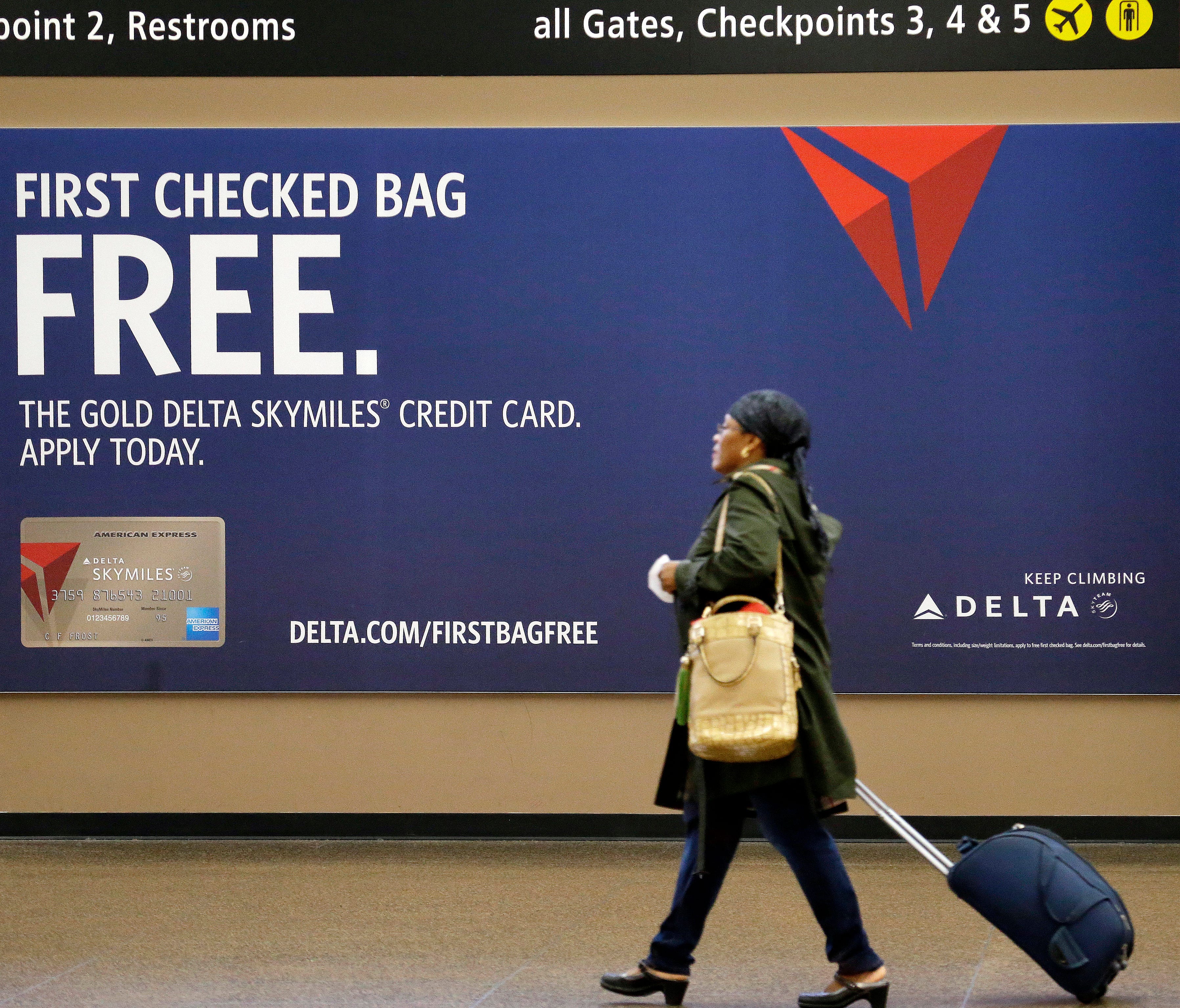 This file photo from March 24, 2015, shows a traveler passing a sign advertising a Delta Air Lines credit card at Seattle-Tacoma International Airport.