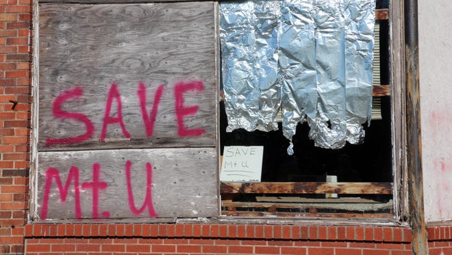 A partially boarded window in downtown Mount Union, on the front of a residence that once was a grocery store, has been scrawled with a plea to preserve the town.