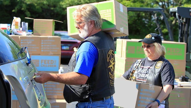 Scott Reed and Pearl Underwood, both members of the Star Touring & Riding Association, load boxes of food and household items into a vehicle at the DaySpring Church in Forest Park. The group was distributing 25-pound boxes of food and 10-pound boxes of home essentials to 800 needy families.